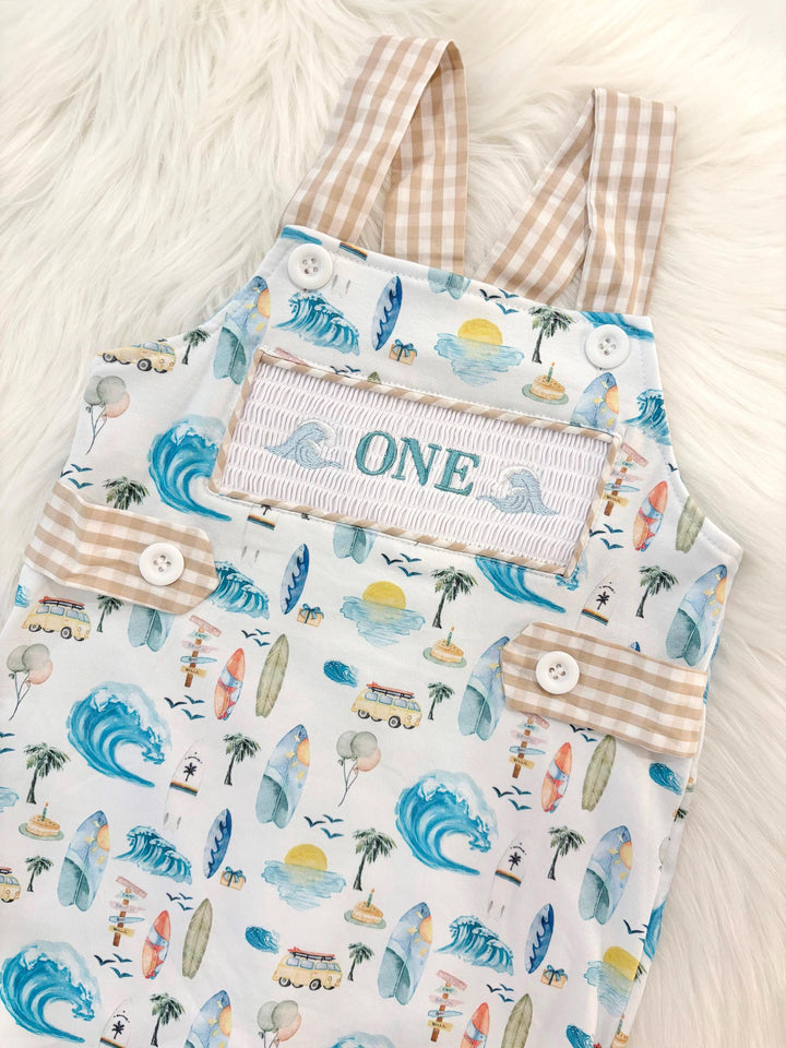 the big one first birthday boy romper my first wave summer beach surfer aqua blue tan white gingham yellow smash cake outfit overalls, ONE smocked romper first birthday beach party surfing, ocean embroidered smocked spring summer 1st birthday boy outfit romper baby boys cake smash outfit, the mod mango baby boutique co