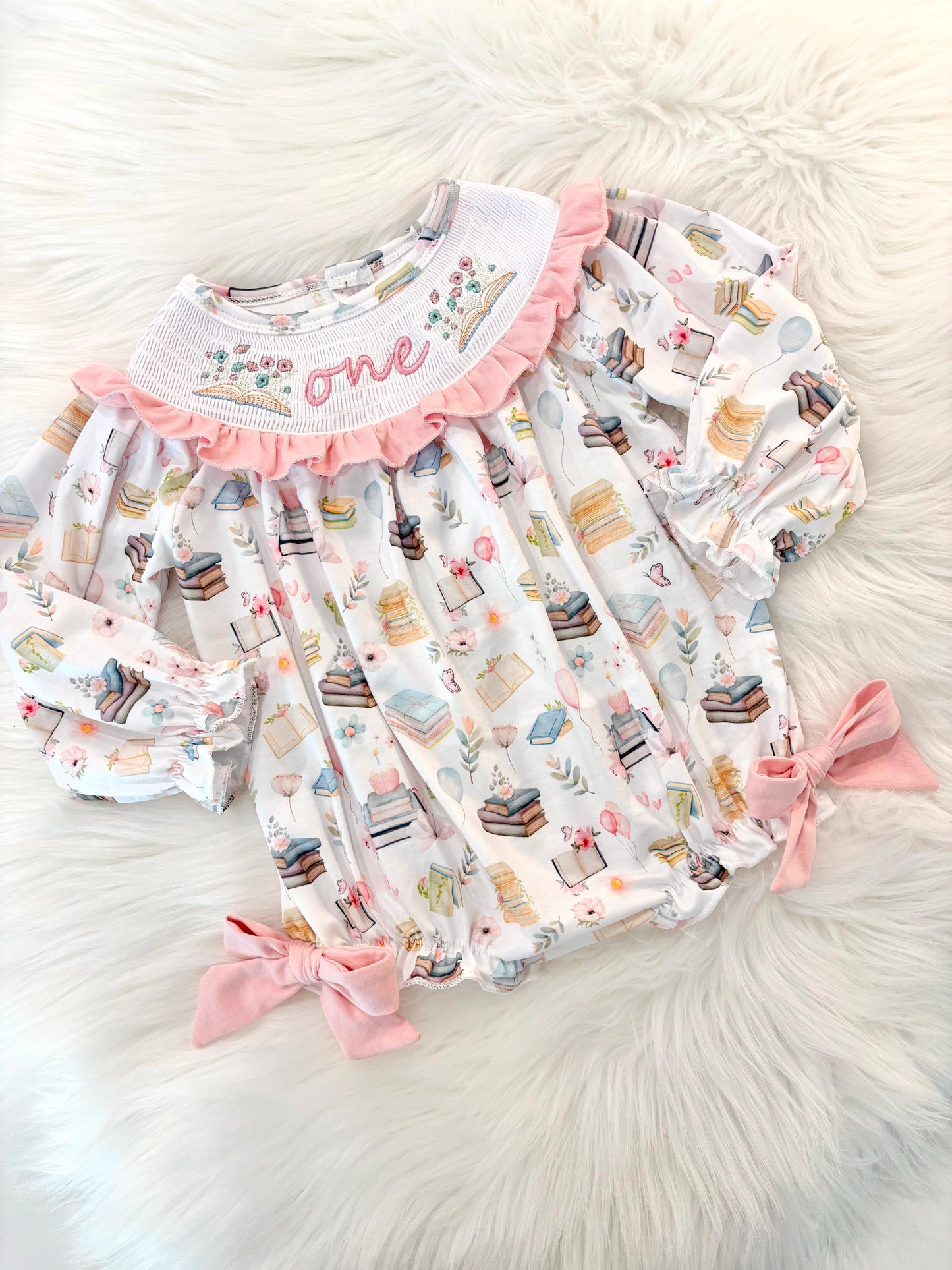 pink books flowers bows first birthday girl romper blush pink blue pastel floral and white outfit, pink and white smocked bubble romper first birthday chapter one books ruffle bows embroidered smocked long sleeve 1st birthday outfit romper baby girls, the mod mango, the mod mango baby co baby boutique