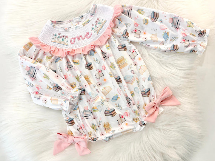 pink books flowers bows first birthday girl romper blush pink blue pastel floral and white outfit, pink and white smocked bubble romper first birthday chapter one books ruffle bows embroidered smocked long sleeve 1st birthday outfit romper baby girls, the mod mango, the mod mango baby co baby boutique