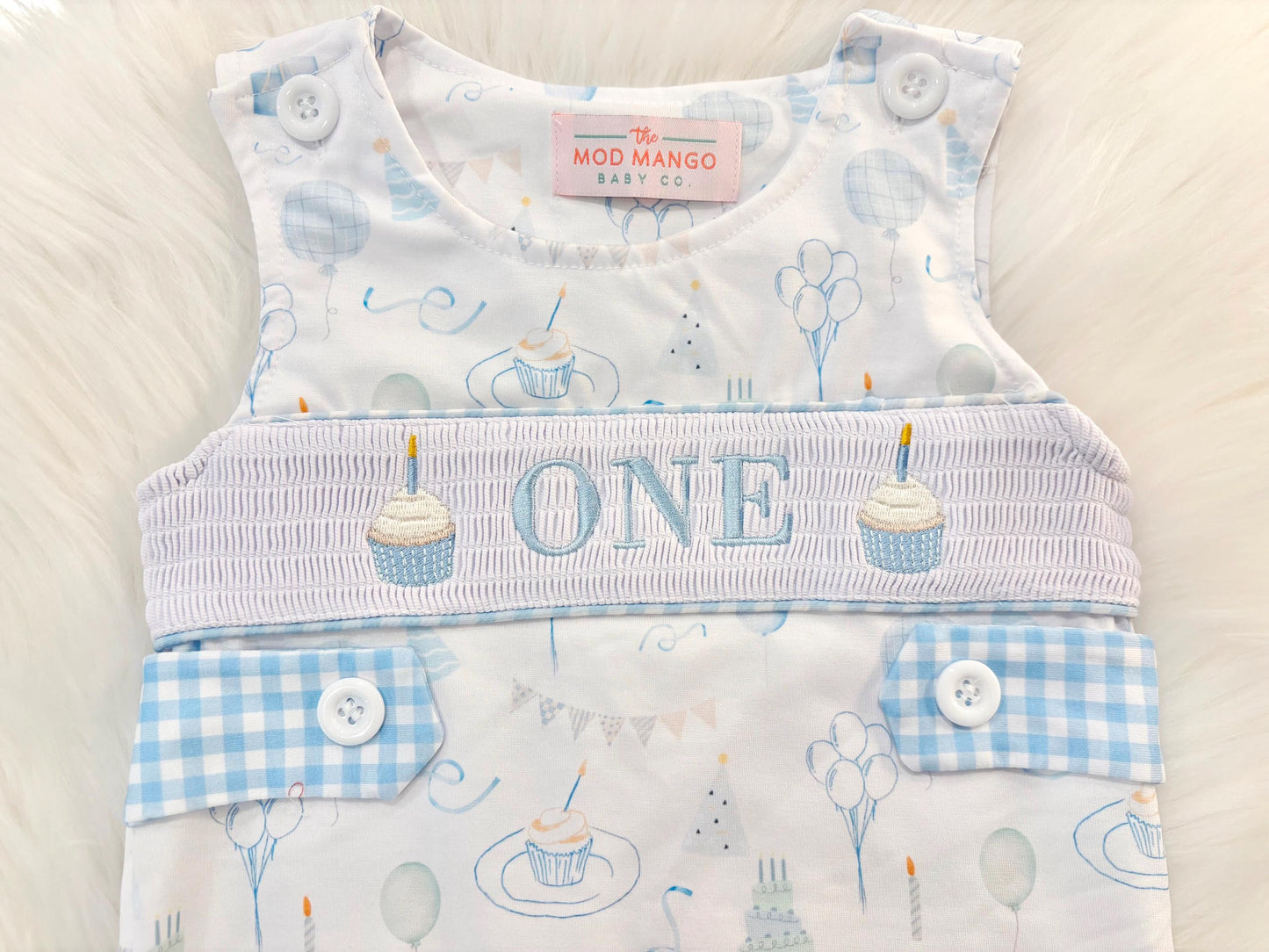blue and white gingham checkered first birthday cupcakes romper pants outfit, one is fun first birthday outfit, it&#39;s fun to be one first birthday boy romper blue green longtalls blue white gingham smash cake outfit overalls, ONE smocked romper first birthday party hats, balloons embroidered smocked spring summer fall 1st birthday boy outfit romper baby boys 1st birthday cake smash outfit, the mod mango baby boutique co, boys first birthday outfit theme
