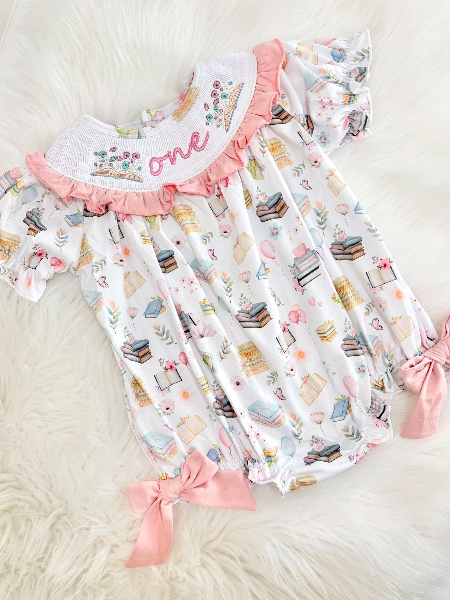 pink books flowers bows first birthday girl romper blush pink blue pastel floral and white outfit, pink and white smocked bubble romper first birthday chapter one books ruffle bows embroidered smocked long sleeve 1st birthday outfit romper baby girls, the mod mango, the mod mango baby co baby boutique