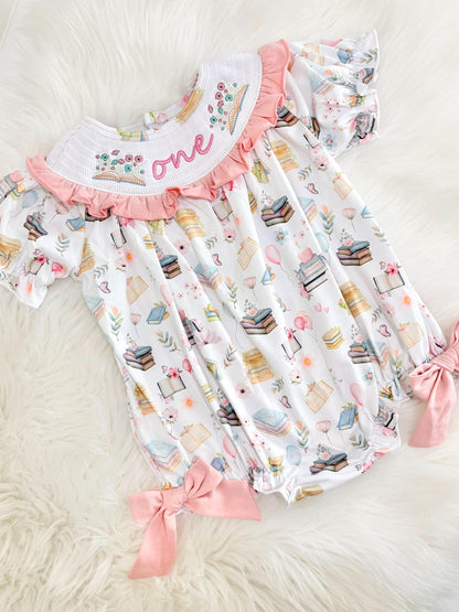 pink books flowers bows first birthday girl romper blush pink blue pastel floral and white outfit, pink and white smocked bubble romper first birthday chapter one books ruffle bows embroidered smocked long sleeve 1st birthday outfit romper baby girls, the mod mango, the mod mango baby co baby boutique