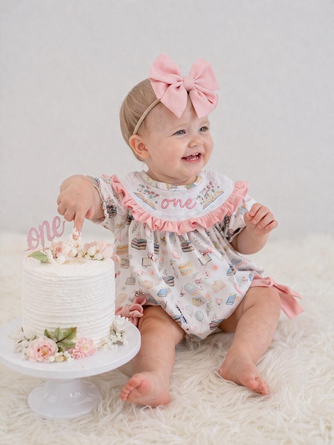 pink books flowers bows first birthday girl romper blush pink blue pastel floral and white outfit, pink and white smocked bubble romper first birthday chapter one books ruffle bows embroidered smocked long sleeve 1st birthday outfit romper baby girls, the mod mango, the mod mango baby co baby boutique