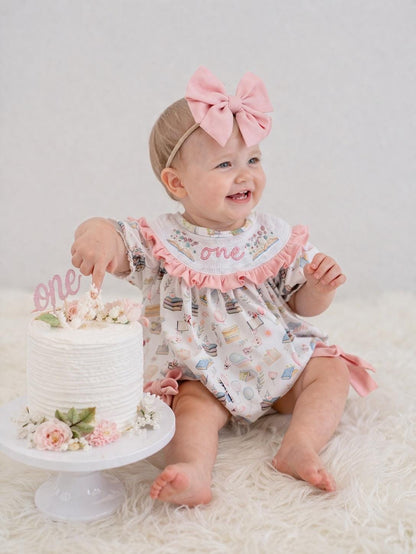 pink books flowers bows first birthday girl romper blush pink blue pastel floral and white outfit, pink and white smocked bubble romper first birthday chapter one books ruffle bows embroidered smocked long sleeve 1st birthday outfit romper baby girls, the mod mango, the mod mango baby co baby boutique