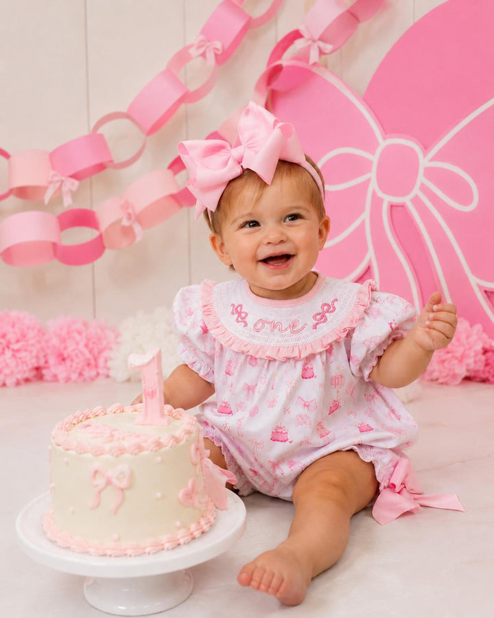 pink bow first birthday girl romper pink and white outfit, pink white smocked bubble romper first birthday winter bows ruffle bows  embroidered smocked long sleeve 1st birthday outfit romper baby girls the mod mango baby boutique